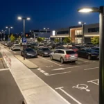 Oświetlony parking o zmierzchu z rzędem latarni LED i oznakowanymi miejscami postojowymi